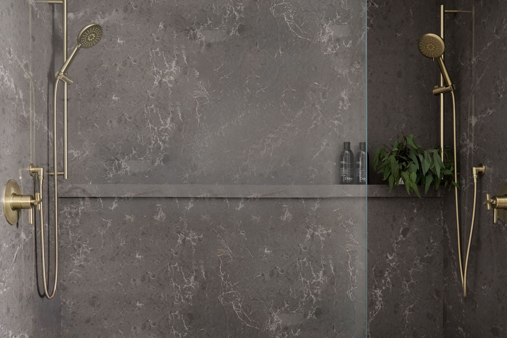 Modern shower with gray walls, gold fixtures, and a wooden stool with a white towel.