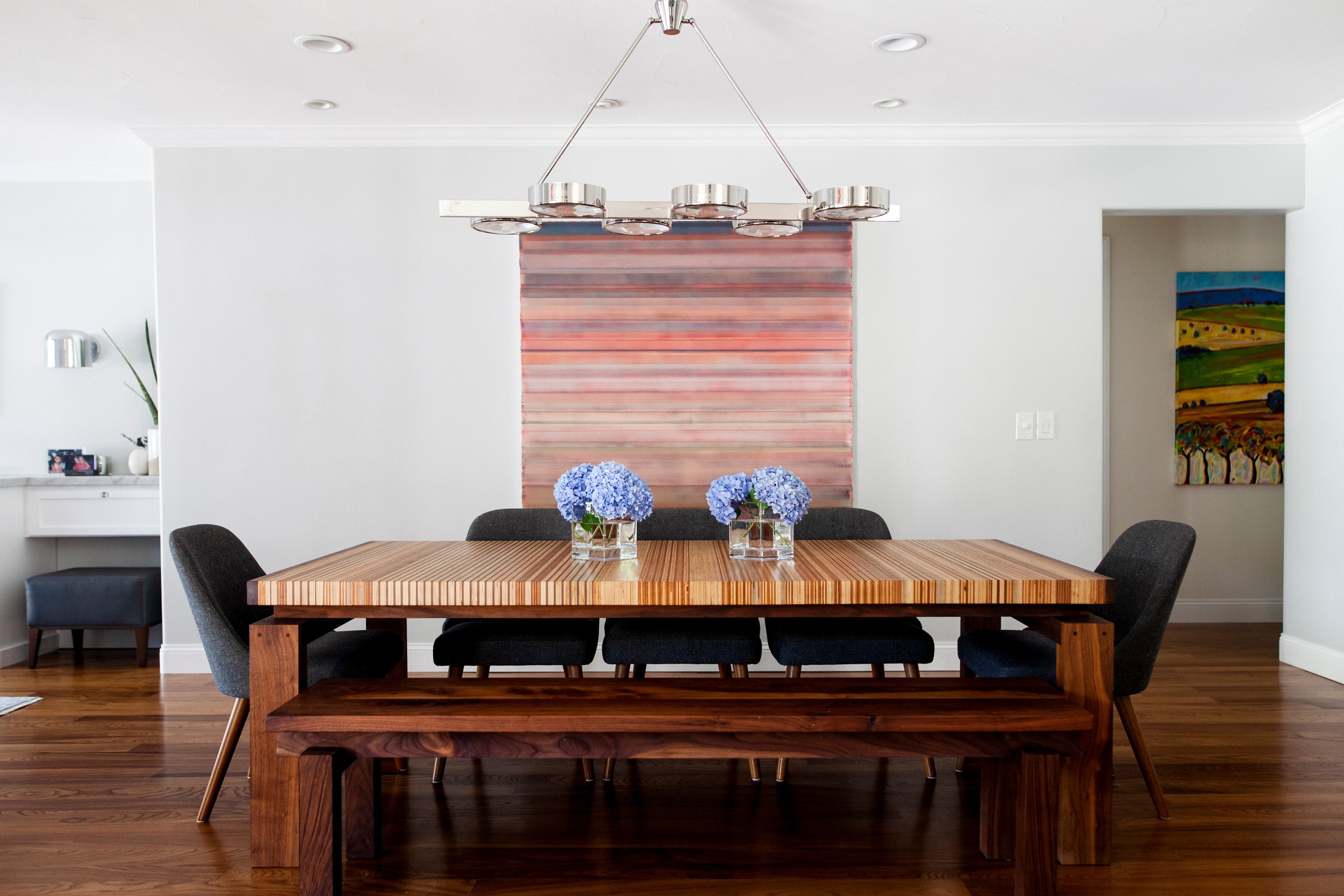 Dining room with a wooden table and chairs, featuring a striped wall hanging.